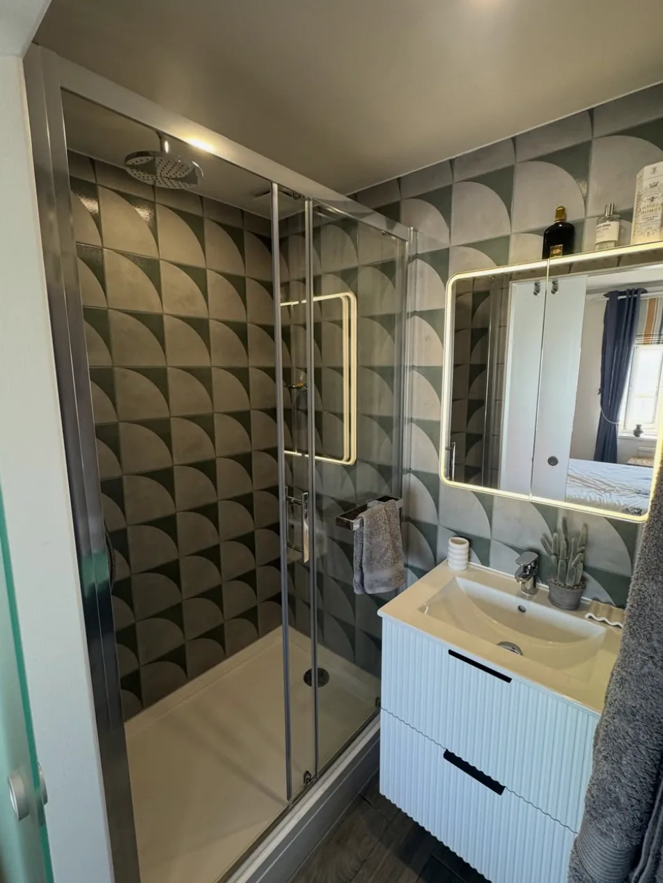 Completed modern shower room with geometric wall finish by Infinite Plumbing & Heating