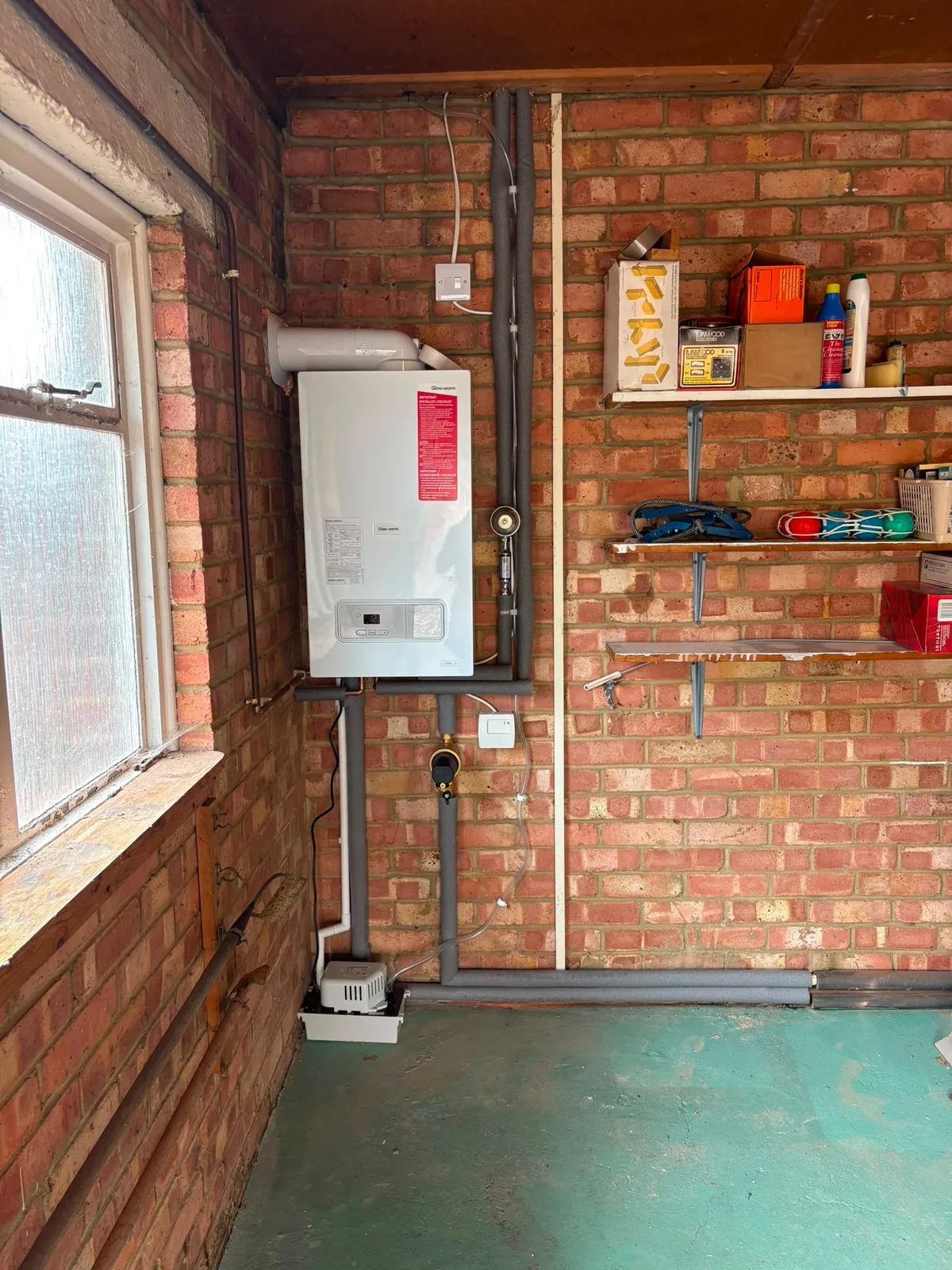 Wall-mounted boiler installation in a garage by Infinite Plumbing & Heating
